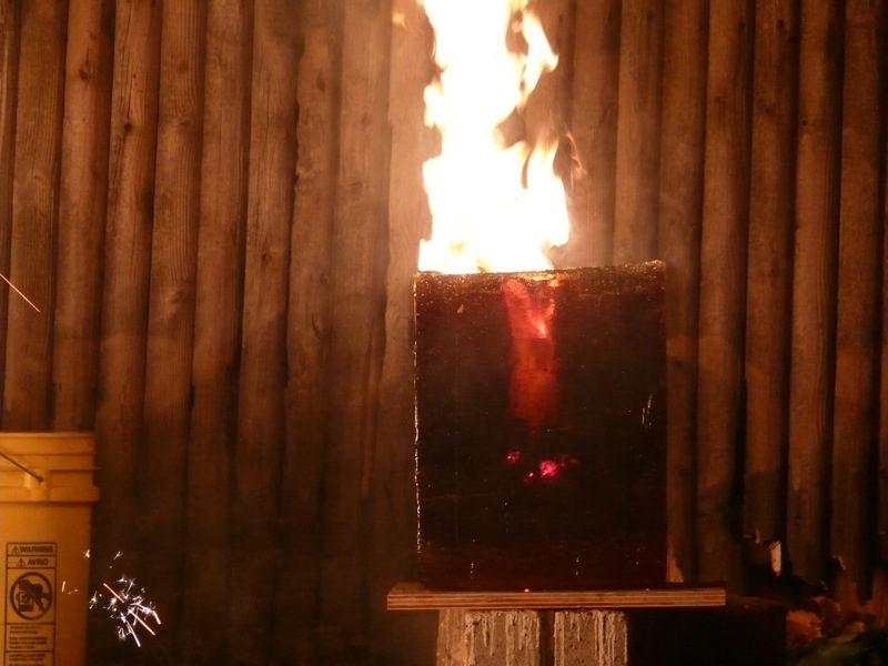 An iron pour in action, with flames rising from a container.