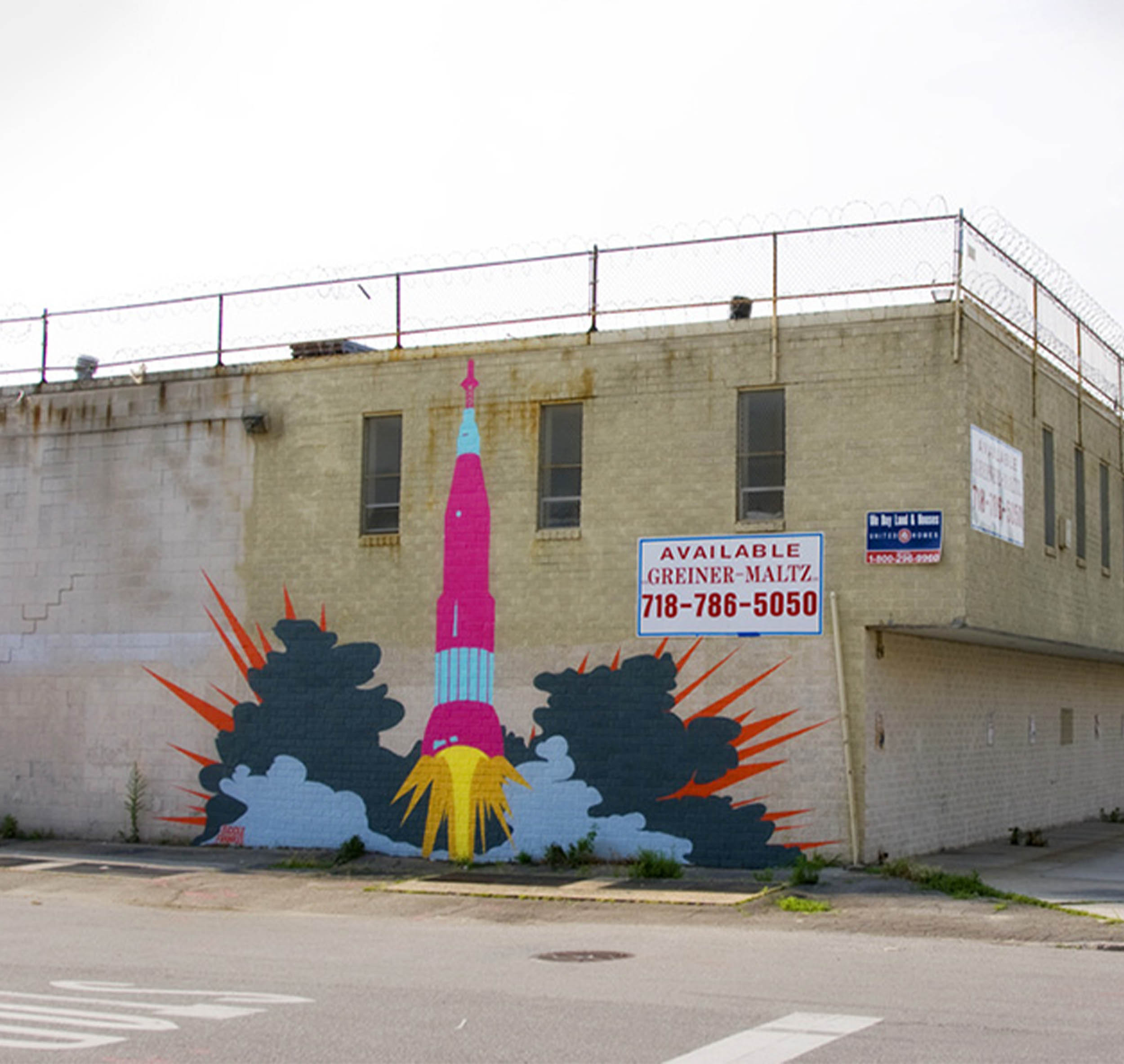 Photograph of a pink rocketship mural painted on the side of a building.