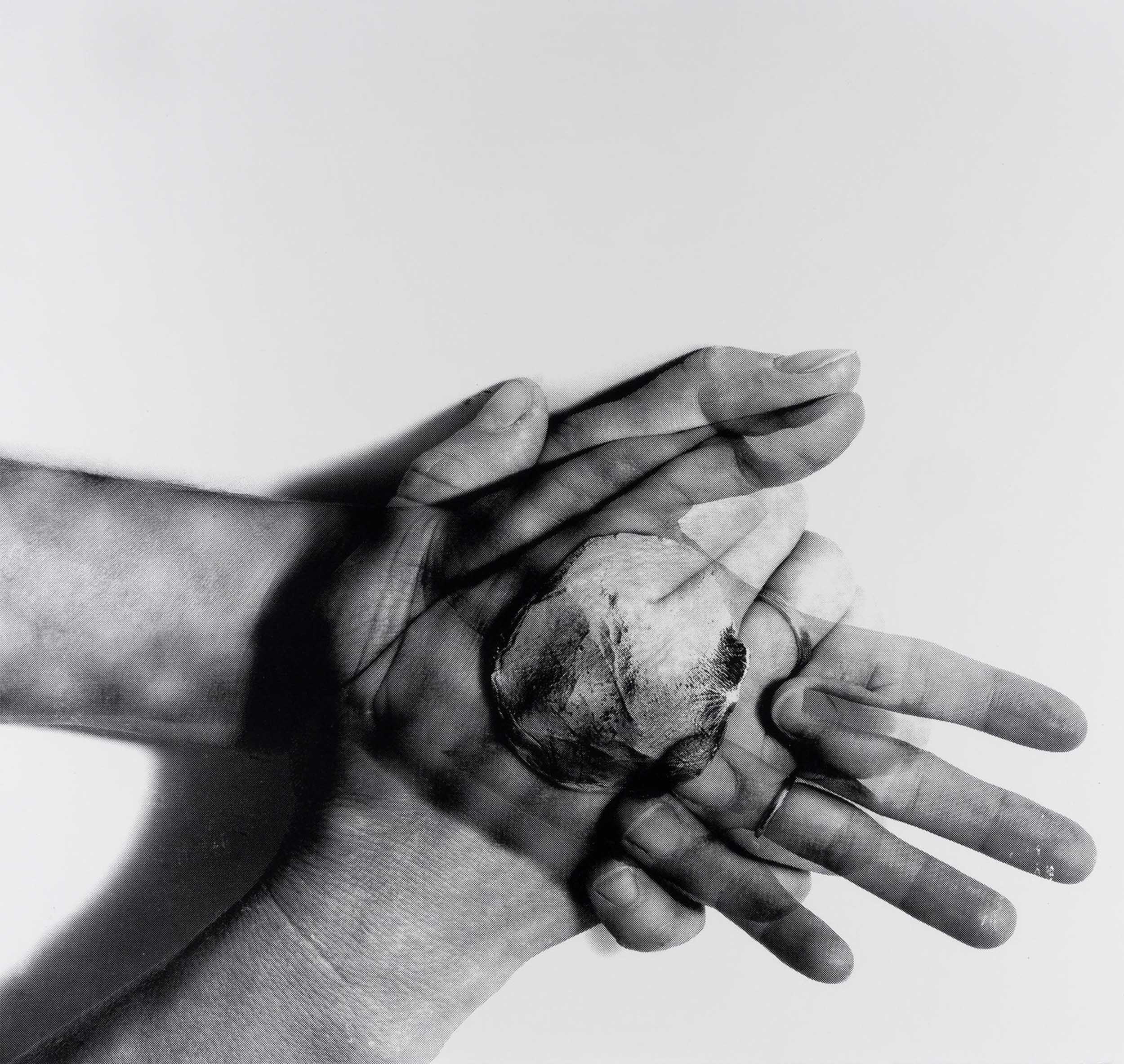 Silkscreen of two hands pressed together at the palm with a ceramic disk pressed between them. The disk is visible due to transparent image overlay similar to an x-ray.