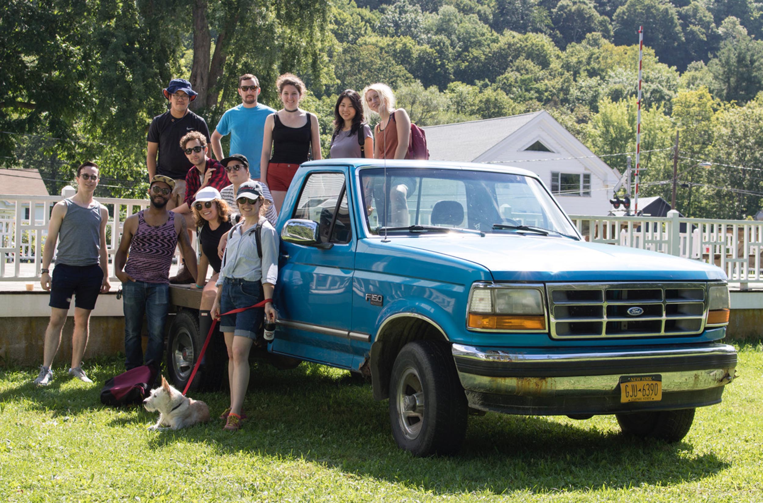 Several people who are participants in a retreat pose next to a pickup truck in the summer sunshine.