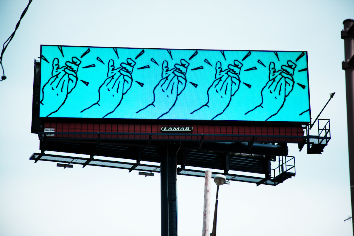 A photograph of a billboard depicting an animation of clapping hands.
