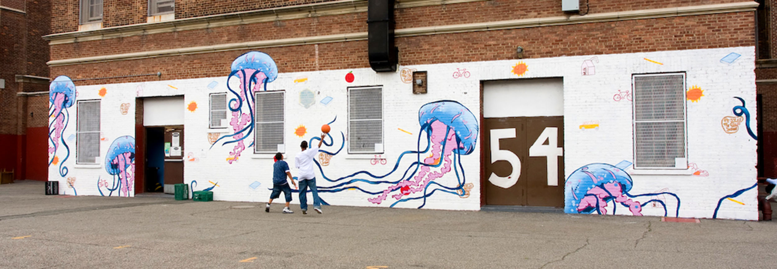Mural on the side of a school depicting several jellyfish on a white backdrop with bicycles, books, and germs.
